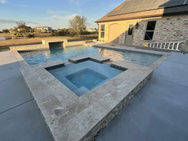 Custom swimming pool with raised spa, stone coping, and waterfall feature